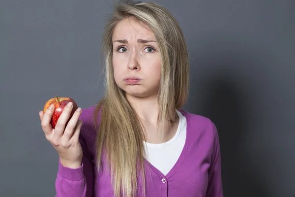 Uttråkad 20s blond flicka inte gillar smaken av ett rött äpple — Stockfoto