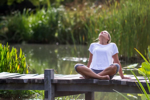 Zen 20 's blond girl relaxing, pond environment — стоковое фото