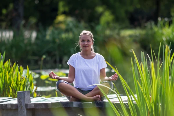 Zen 20 's blond girl thinking, pond environment — стоковое фото