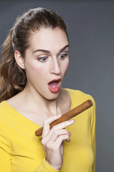 Mujer joven aturdida sosteniendo un cigarro grande como futura mujer de negocios exitosa —  Fotos de Stock