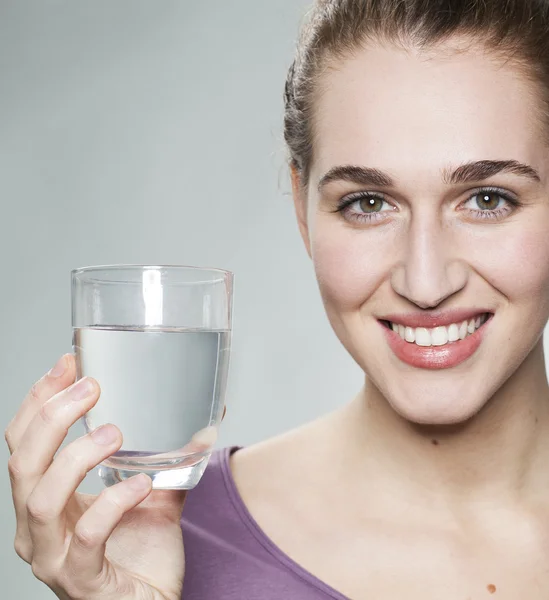 Chica serena de 20 años mostrando un vaso de agua dulce del grifo o mineral —  Fotos de Stock