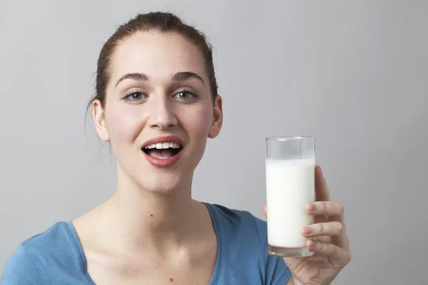 Schöne 20er Jahre Mädchen glücklich, ein Glas Milch oder weißes Getränk zu zeigen — Stockfoto