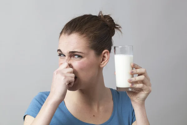 20er Jahre Mädchen hält ihre Nase, um Milch zu trinken zu vermeiden — Stockfoto