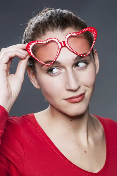 Hermosa mujer de 20 años mirando por encima de sus gafas rojas divertidas —  Fotos de Stock