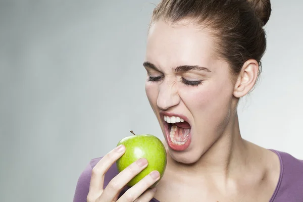 hungry 20s girl biting an apple with appetite and thirst