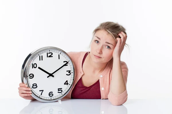 Confus belle jeune femme blonde affichant une horloge — Photo