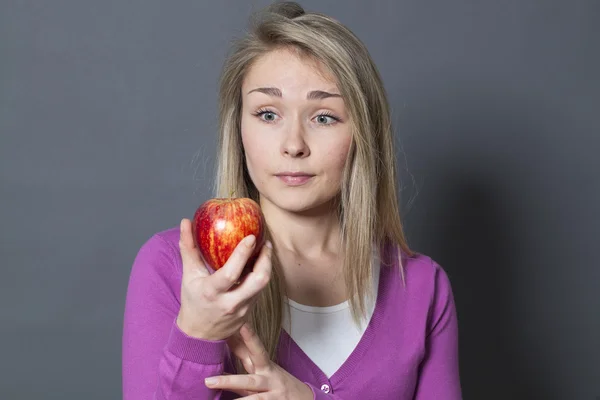 Oskyldiga blond flicka hänförd av ett äpple i handen — Stockfoto