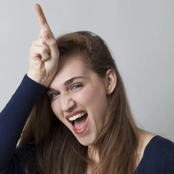 Грайлива молода жінка робить знак L невдах на лобі — стокове фото