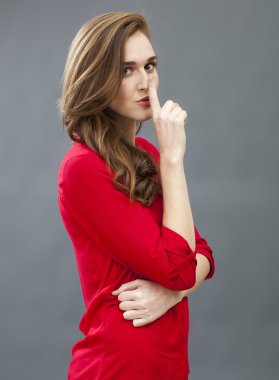 beautiful young woman making things confidential with shut-up sign 