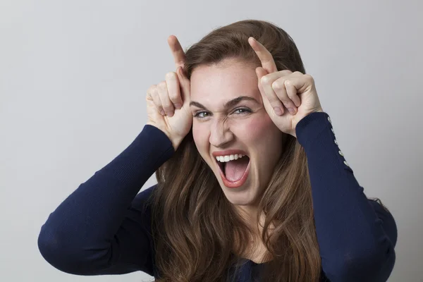 Lachende junge Frau mit Doppelfingerhörnern für freches Zeichen — Stockfoto