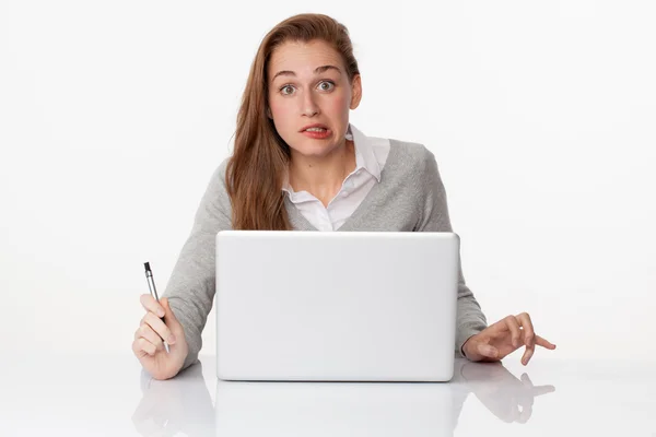 Aterrorizada mujer de 20 años escribiendo en PC en el escritorio blanco escaso — Foto de Stock