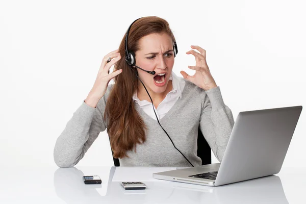 kulaklık ve bilgisayar ile şok altında kızgın 20s çalışan kadın