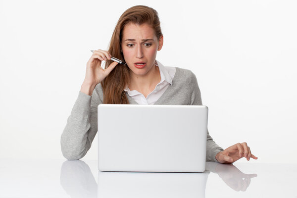 surprised 20s woman writing on pc on sparse white desk