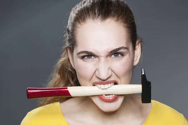 Woedend 20s vrouw bijten hamer voor agressieve handwerk of DIY — Stockfoto