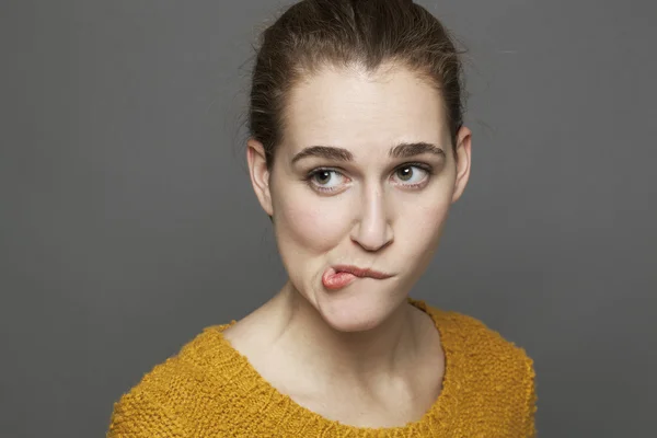 Mujer joven y ansiosa que parece escéptica, mordiéndose los labios por confusión —  Fotos de Stock