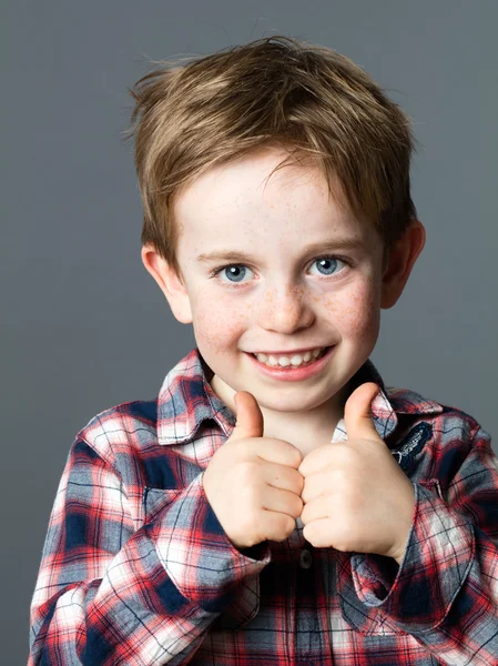 Niño alegre pelo rojo con pecas y pulgares dobles hacia arriba — Foto de Stock