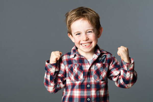 winning young child with tooth missing raising arms for excitement