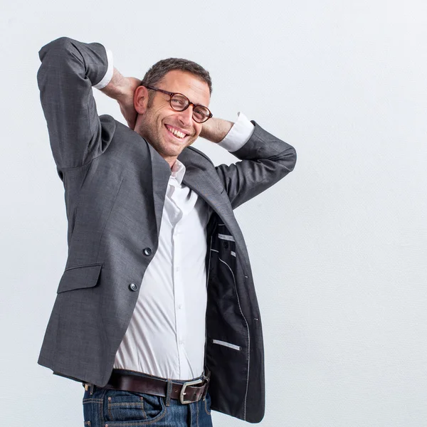 Successo sorridente bell'uomo d'affari in piedi con le braccia dietro la testa — Foto Stock