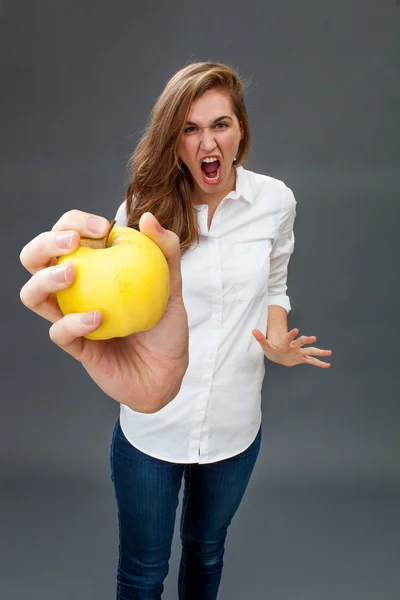 Rasande ung kvinnlig modell skrikande holding ett aptitretande äpple — Stockfoto