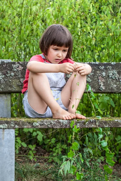 Зосереджена дитина грає з листям плюща, сидячи один в саду — стокове фото