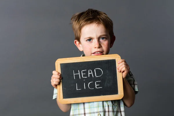 Sad preschool kid protecting from head lice behind school slate — Stock Photo, Image