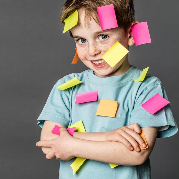 Lindo chico ocupado sonriendo con notas pegajosas por todas partes —  Fotos de Stock