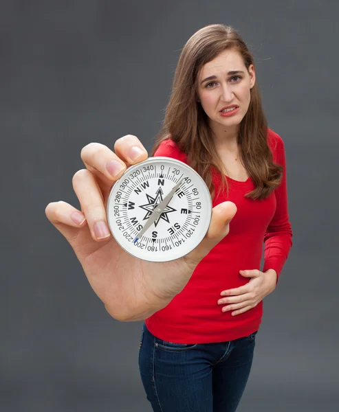 sad young woman holding a large compass feeling sorry