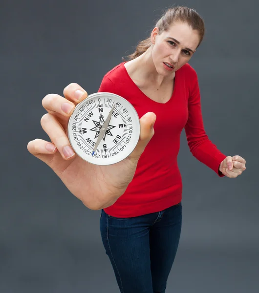 Sceptische jonge vrouw met vechten hand gebaar tegen groot kompas — Stockfoto