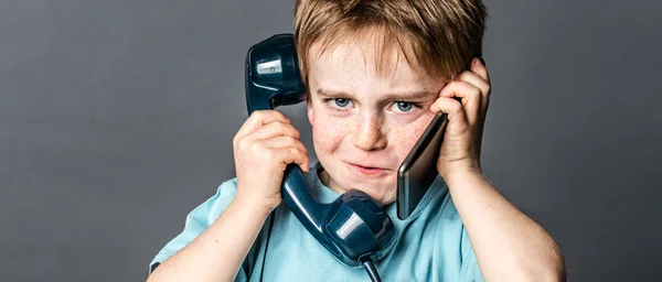 Πονηρό νεαρό αγόρι μιλάει σε παλιό τηλέφωνο και νέο smartphone — Φωτογραφία Αρχείου