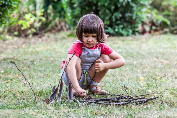 Mutlu küçük çocuk öğrenme twigs ve tüyler ile kurmak için — Stok fotoğraf