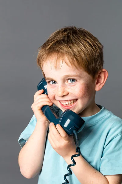 Giggling kleine jongen praten op een blauwe ouderwetse telefoon — Stockfoto