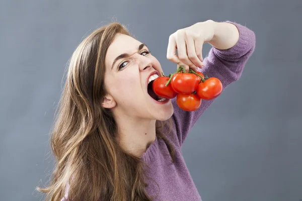 Jeune femme en colère mordre un raisin de tomate pour la nutrition fraîche — Photo