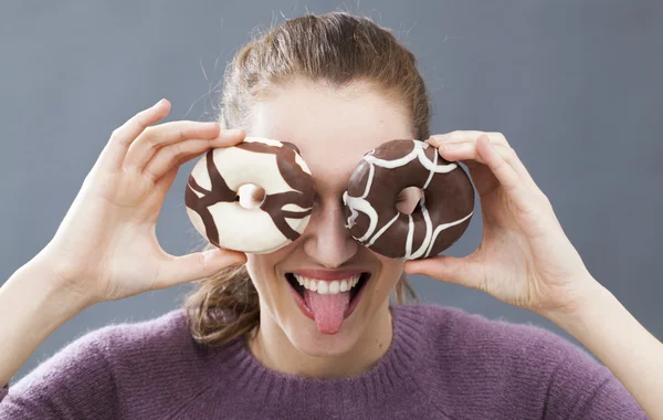 Opgewonden mooi meisje donuts houden op haar ogen voor grap — Stockfoto