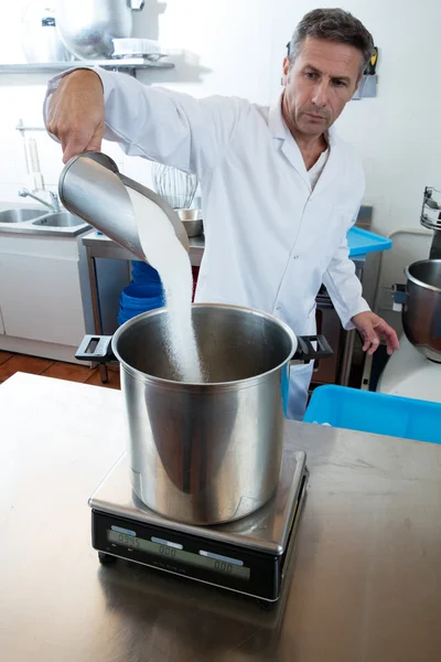 Profesional masculino de mediana edad con bata de laboratorio blanca vertiendo azúcar — Foto de Stock