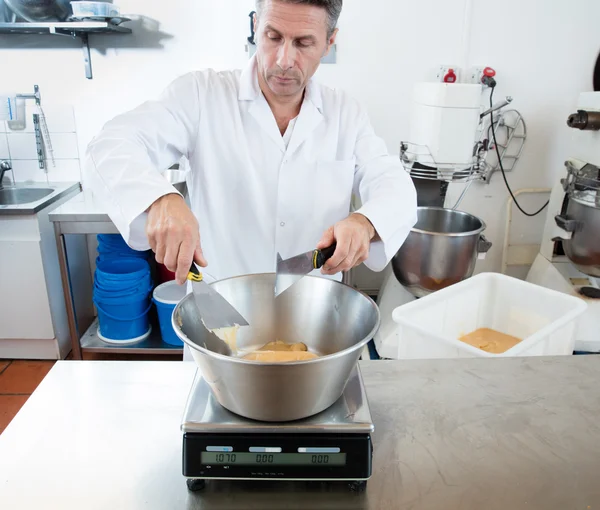 Cozinheiro macho pesando mel com uma espátula em laboratório comercial — Fotografia de Stock