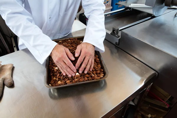 Manos seleccionando almendras asadas para la especialidad de turrón dulce — Foto de Stock