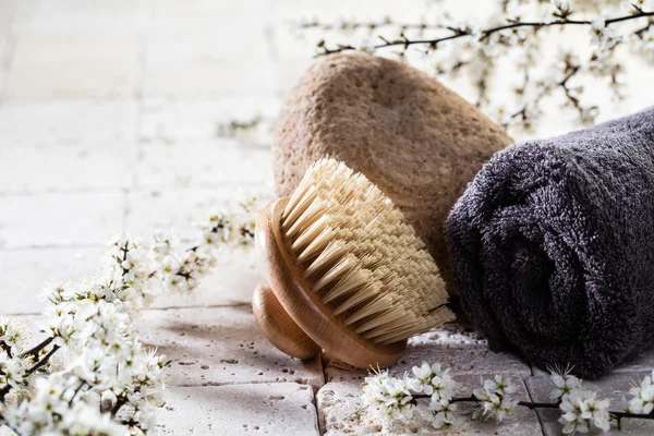 Körperbürste und Handtuch über Stein und Blumen für den Wellnessbereich — Stockfoto