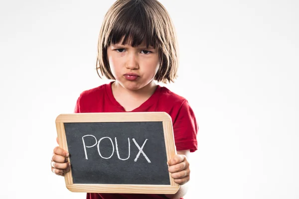 Unhappy young girl behind a school slate with 'poux' written — Stock Photo, Image