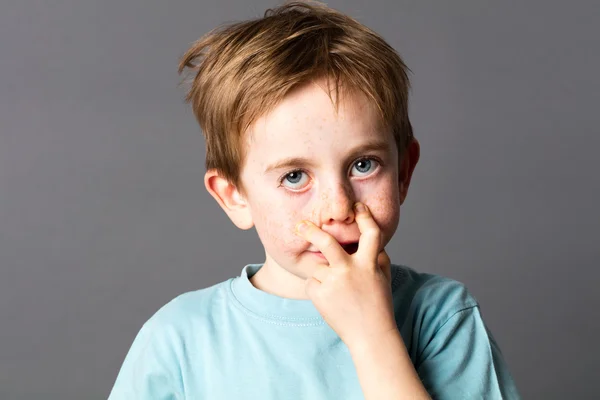 Divertido niño pequeño con ojos azules haciendo una mueca fea —  Fotos de Stock