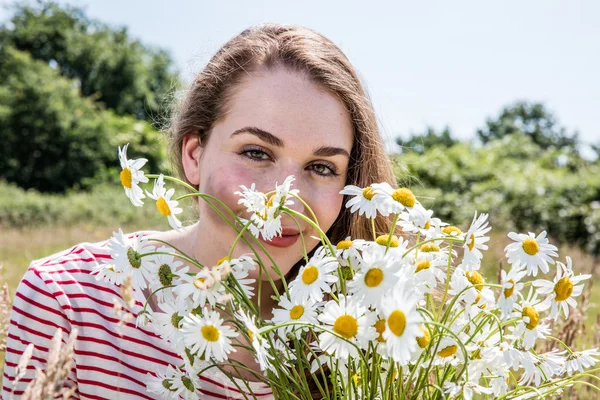 gorgeous young woman smiling with camomile flowers for natural beauty