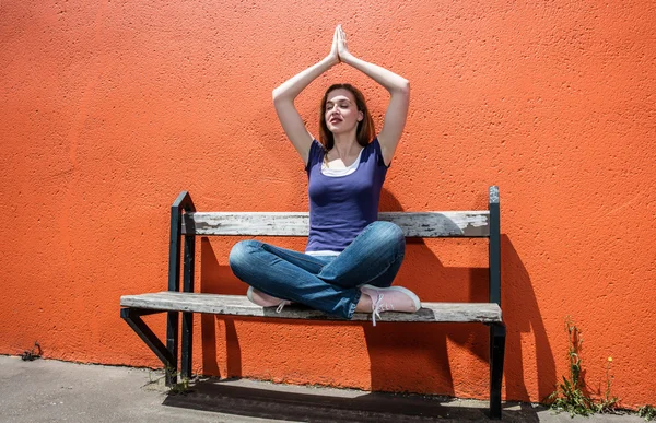 Pregando bella ragazza godendo rilassante sulla panchina in posizione yoga — Foto Stock