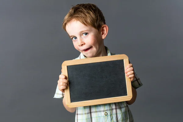 Niño descarado mostrando una pizarra de escritura vacía para el aprendizaje escolar —  Fotos de Stock