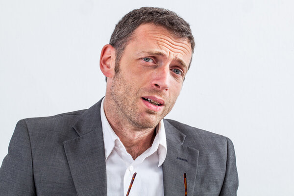 смущенный бизнесмен средних лет, выглядящий виновным и стыдившимся
