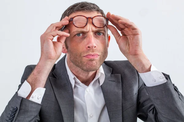 Uomo d'affari scettico con gli occhiali sulla fronte per sospetto — Foto Stock