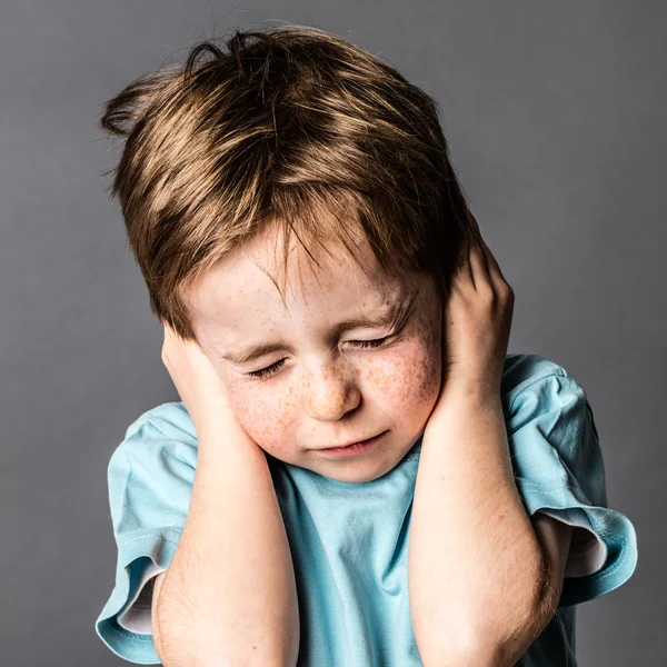 Pequeño niño asustado cerrando oídos y ojos contra la violencia doméstica Imagen De Stock
