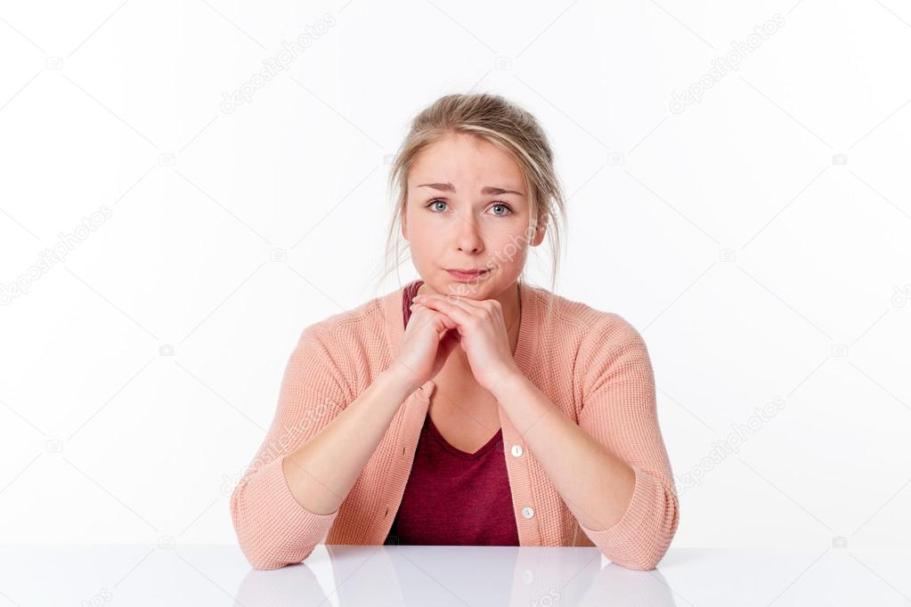 unhappy young blond woman sitting, apologizing and feeling sorry