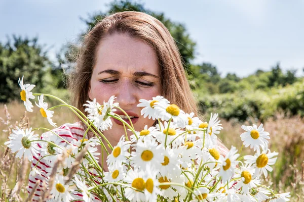 Φτάρνισμα κορίτσι με αλλεργίες ή πυρετό εκ χόρτου μυρίζοντας λουλούδια Μαργαρίτα — Φωτογραφία Αρχείου