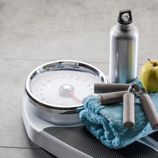 Hand grips, aluminium flask and apple on gym floor, copyspace — Stock Photo, Image