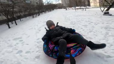 Mutlu kış aile eğlenceleri. Baba altı yaşındaki oğlunu kışın şişirilebilir kar yolculuğuna çıkarıyor. Çocuk gülüyor ve yolculuğun tadını çıkarıyor, neşeli ve enerjik bir an yaratıyor. Gerçek aile eğlencesi, samimi duygular.