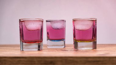 Three colorful shot glasses with iced. A vibrant trio of shot glasses filled with colorful drinks. Selective focus.